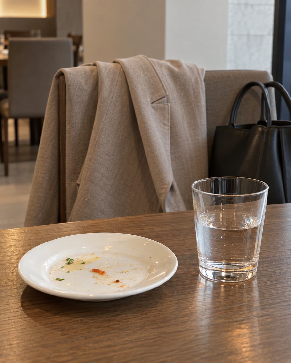 식사한 접시와 물잔 뒤 의자의 겉옷과 개인가방