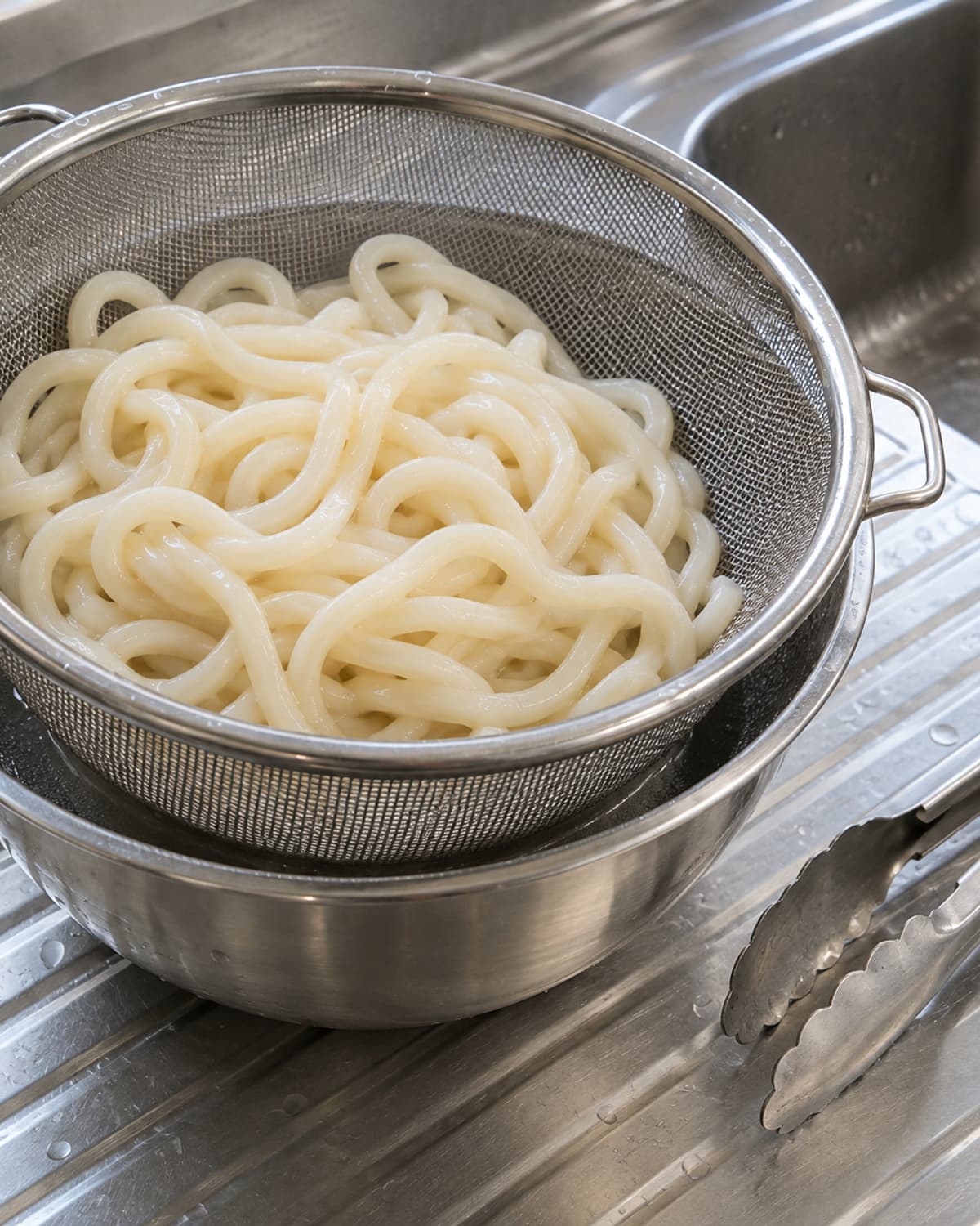 체에 담긴 익힌 우동과 아래 물받침